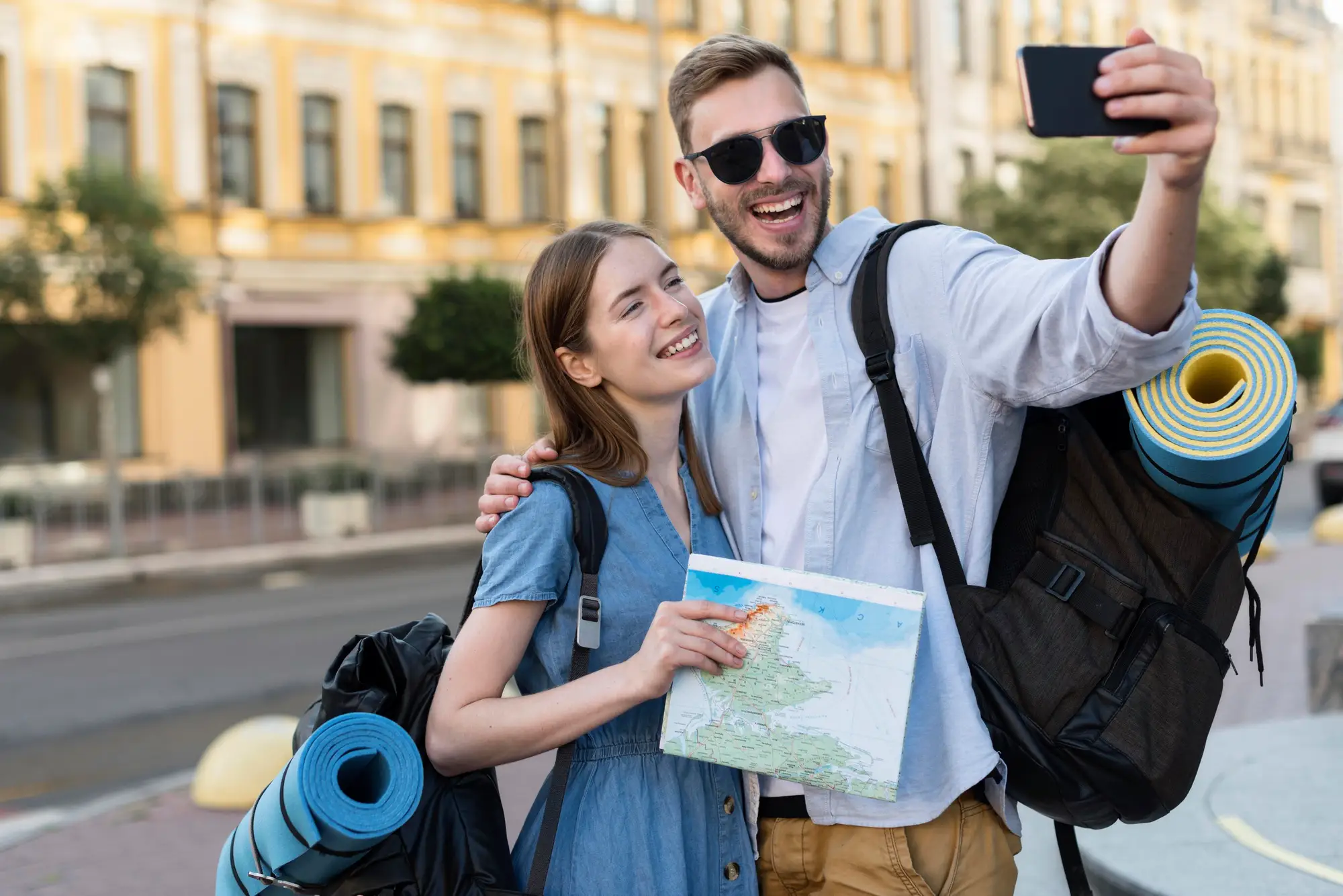 smiley-tourist-couple-taking-selfie-while-carrying-backpacks